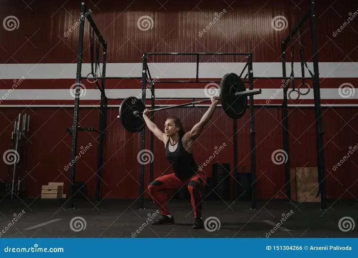 A Weightlifter Lifts a Barbell Above Her Head